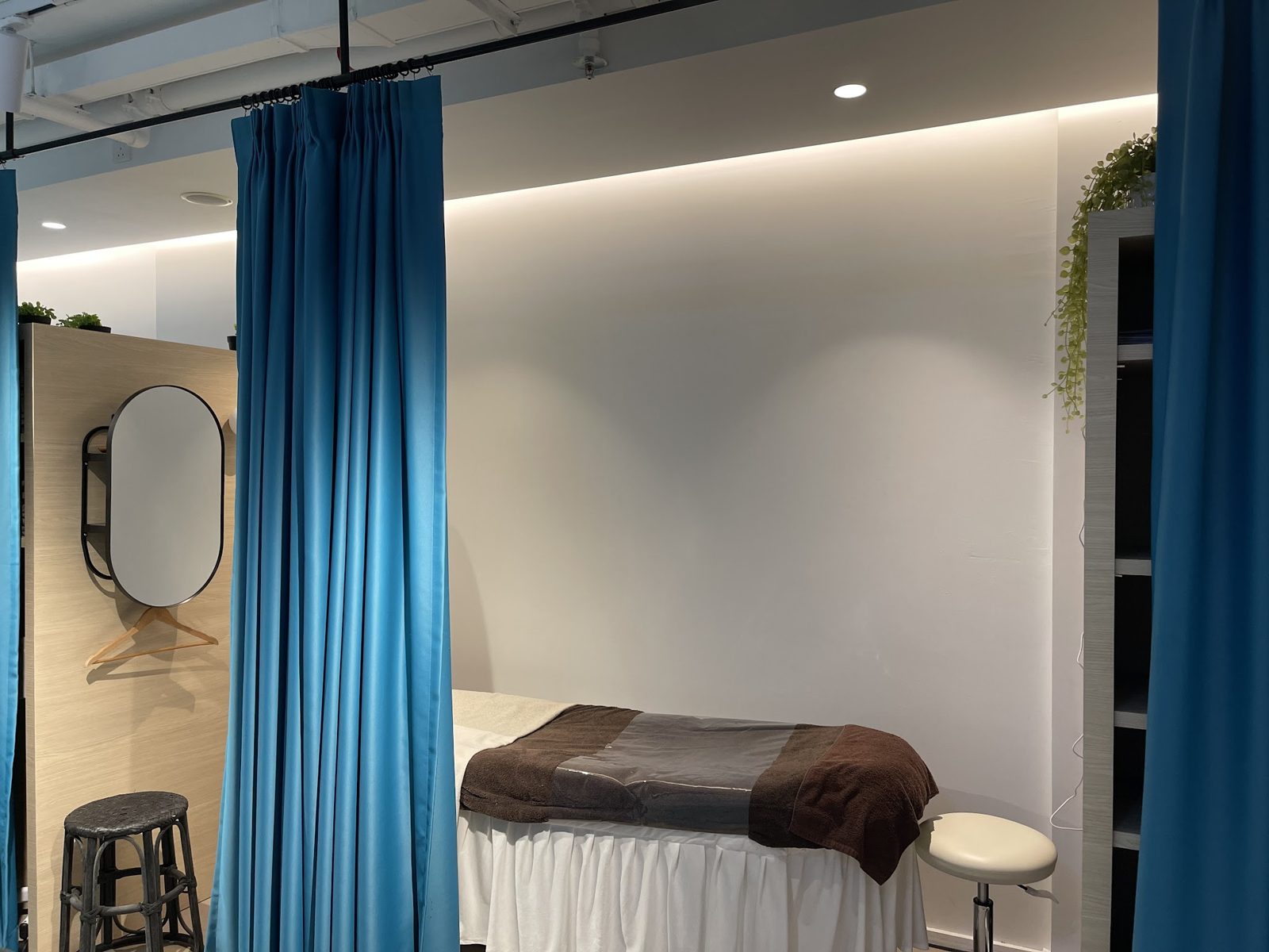 A treatment room with a bed and teal curtains